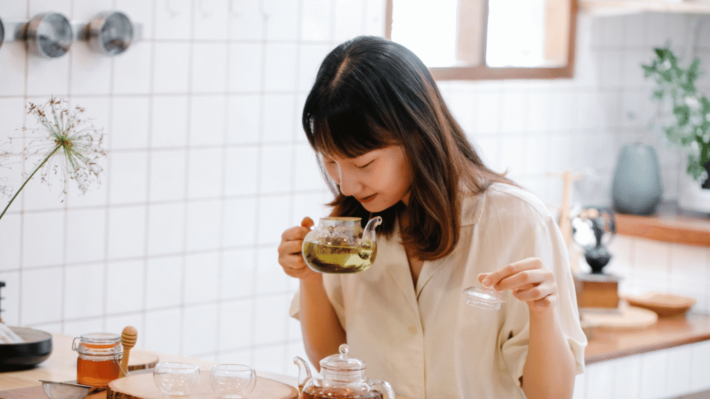 Woman in a bright kitchen preparing herbal detox tea as part of a natural wellness routine