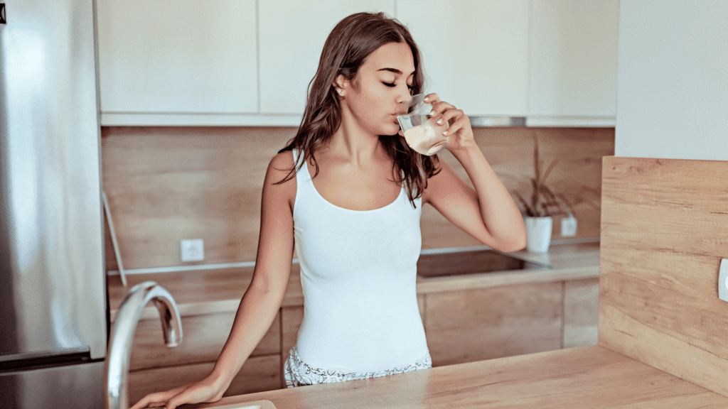 Adult taking natural liver support supplement with water as part of a morning wellness routine.