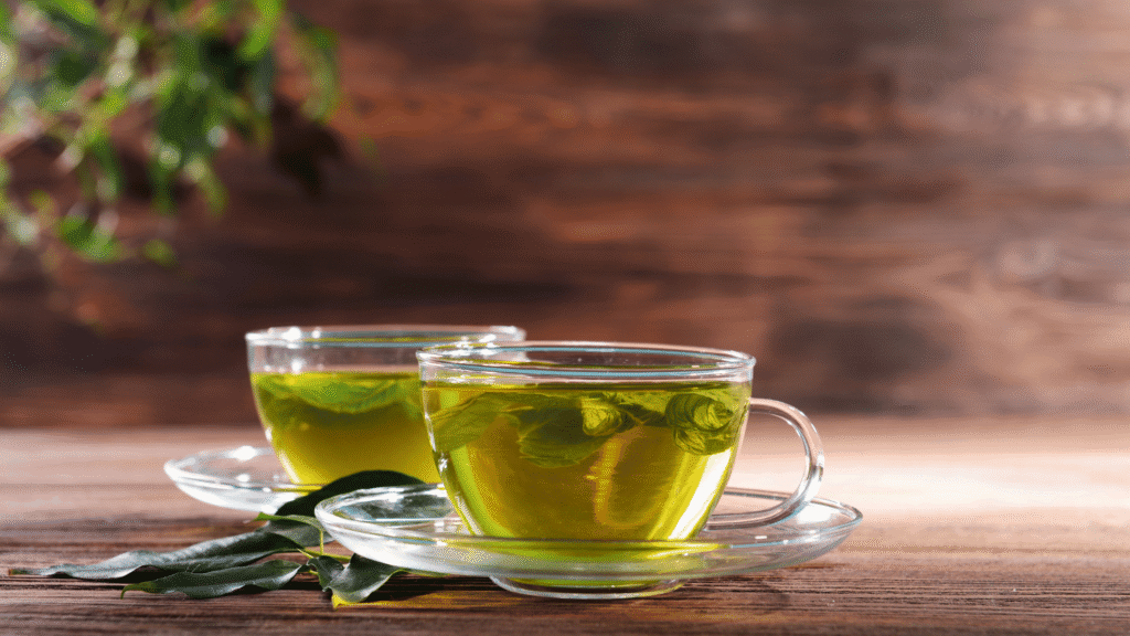 Cups of liver detox teas including green tea, dandelion tea, and boldo on a wooden table.