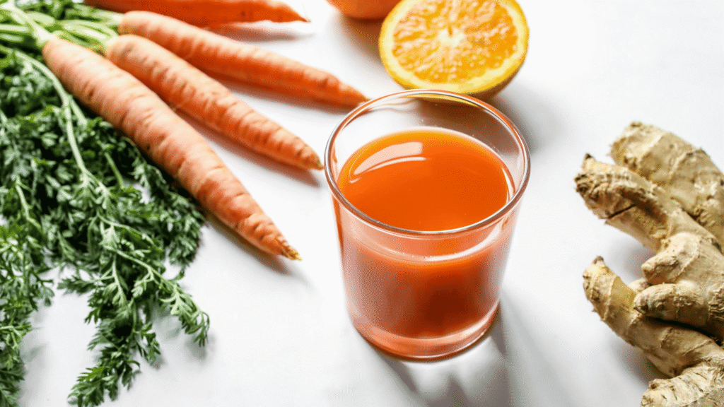 Glass of beet and carrot juice with fresh ingredients like turmeric and orange